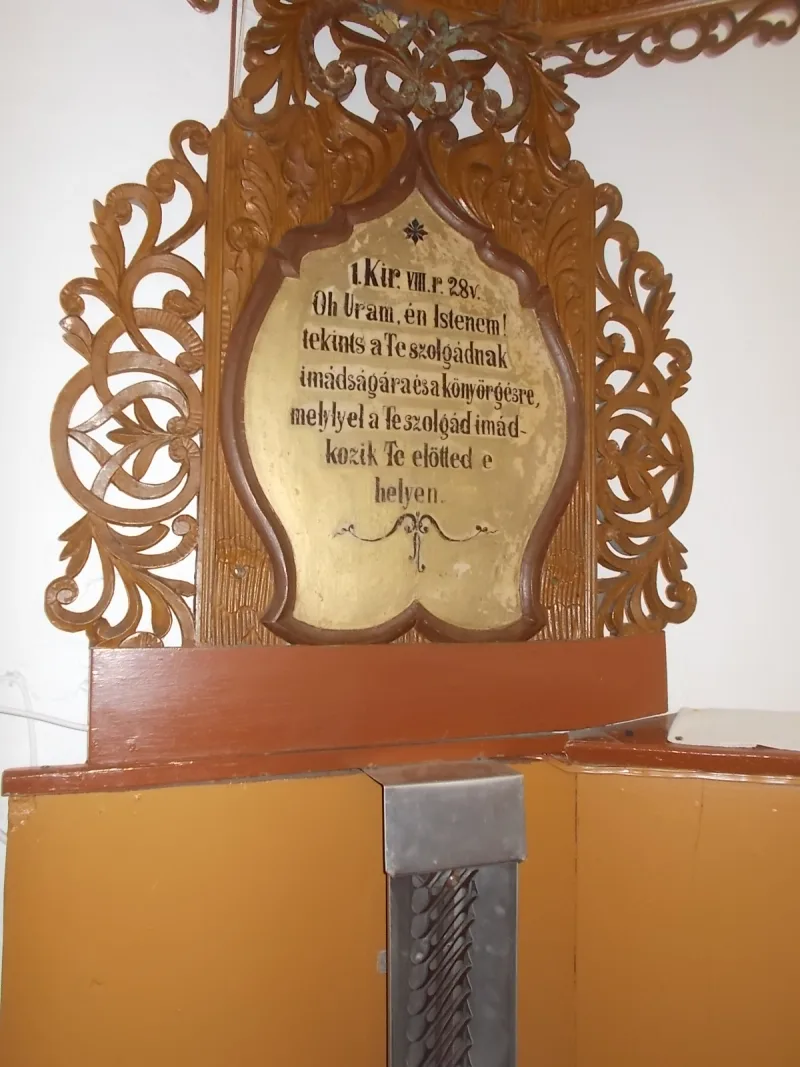 Intérieur d'une église réformée hongroise avec une chaire centrale, un fidèle en prière