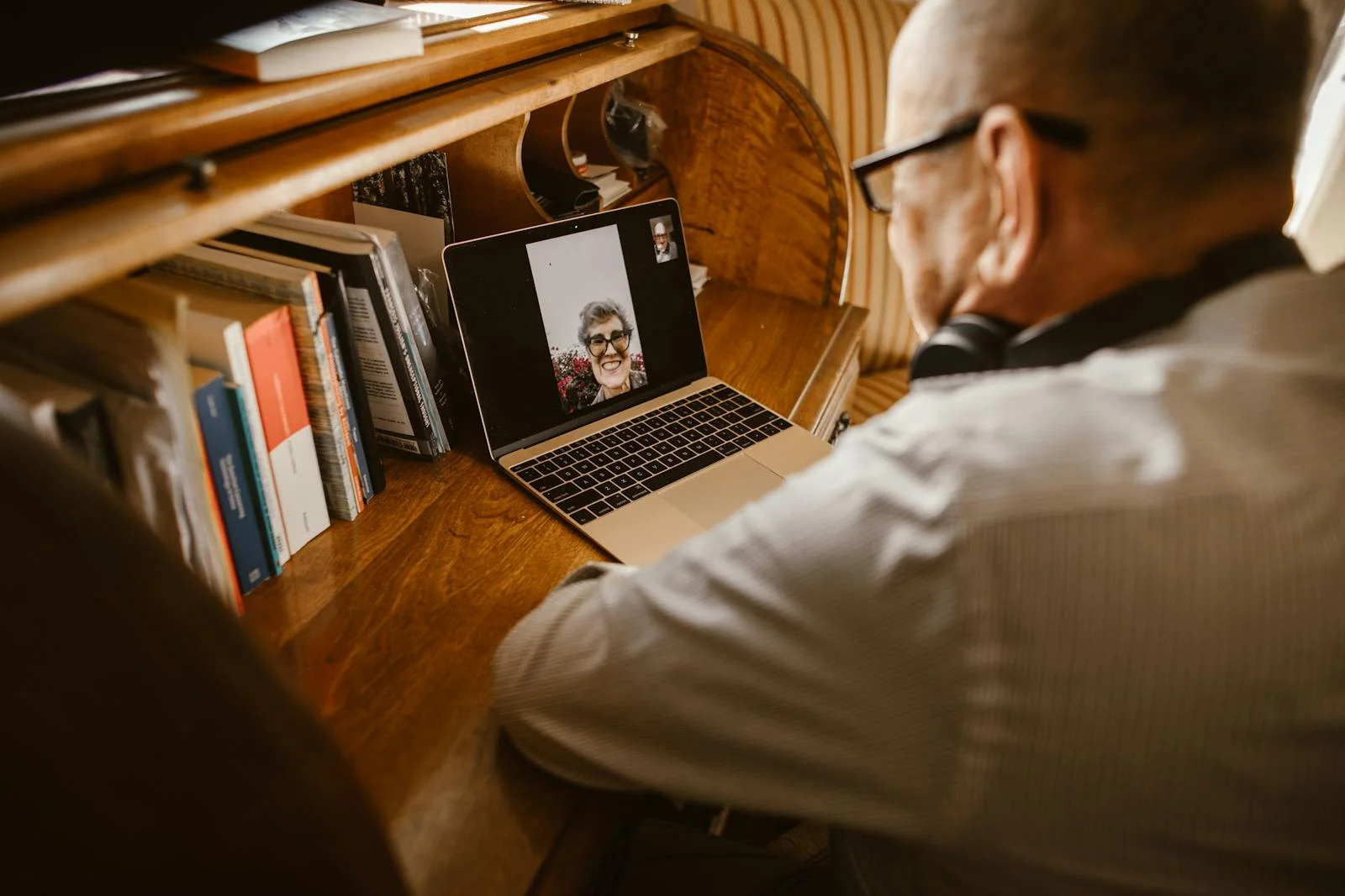 Un homme âgé en appel vidéo sur ordinateur portable : présence et attention malgré la distance.